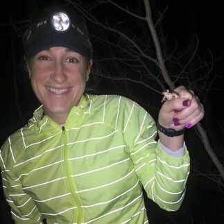 Picture: Mauri wearing a headlamp and posing with a frog in her hand during a night of herping.